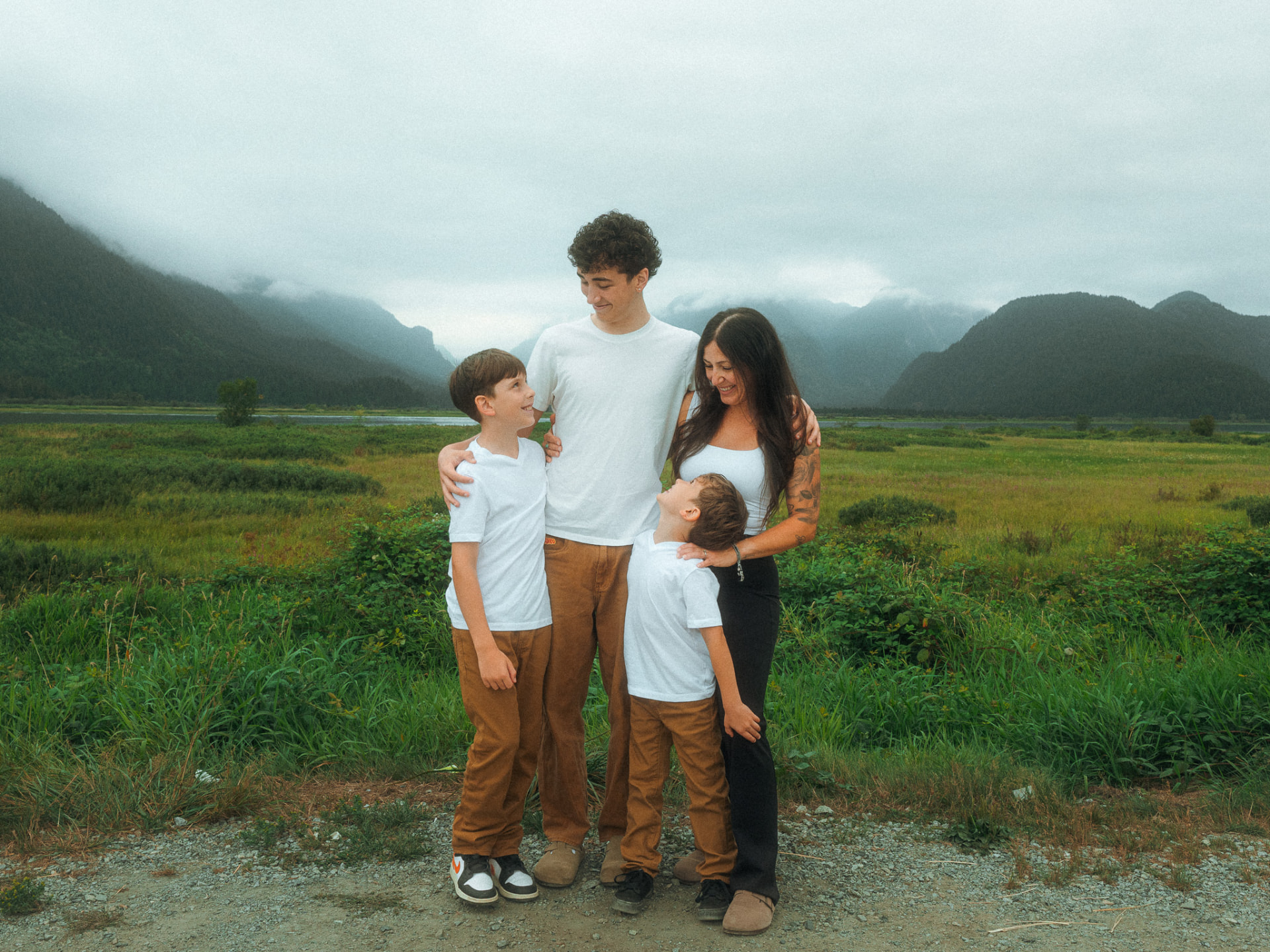 Mother and her three sons sharing a joyful moment in a lush green field near Metro Vancouver