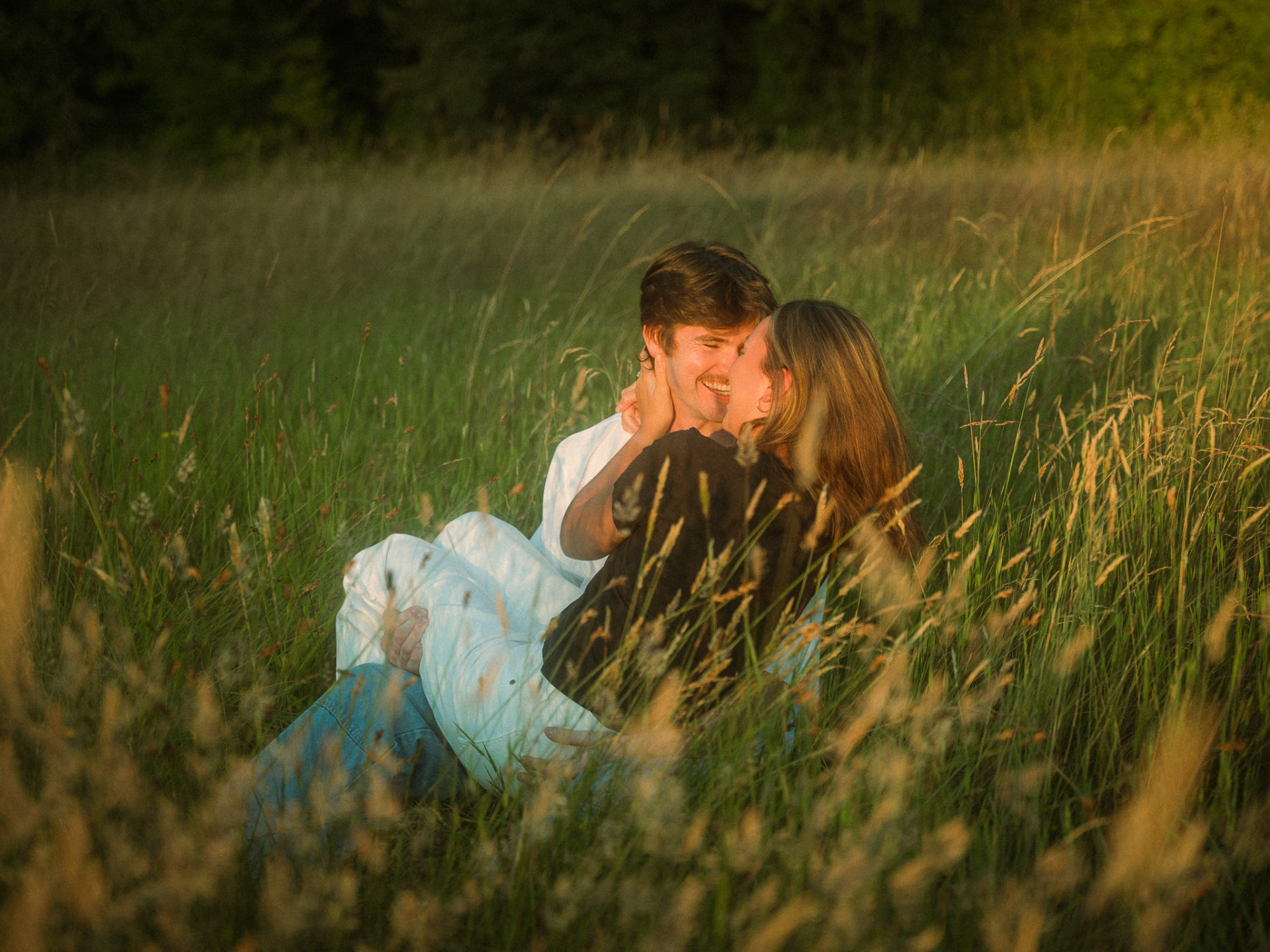Couple sitting together in tall golden-hour grass during a Metro Vancouver engagement session