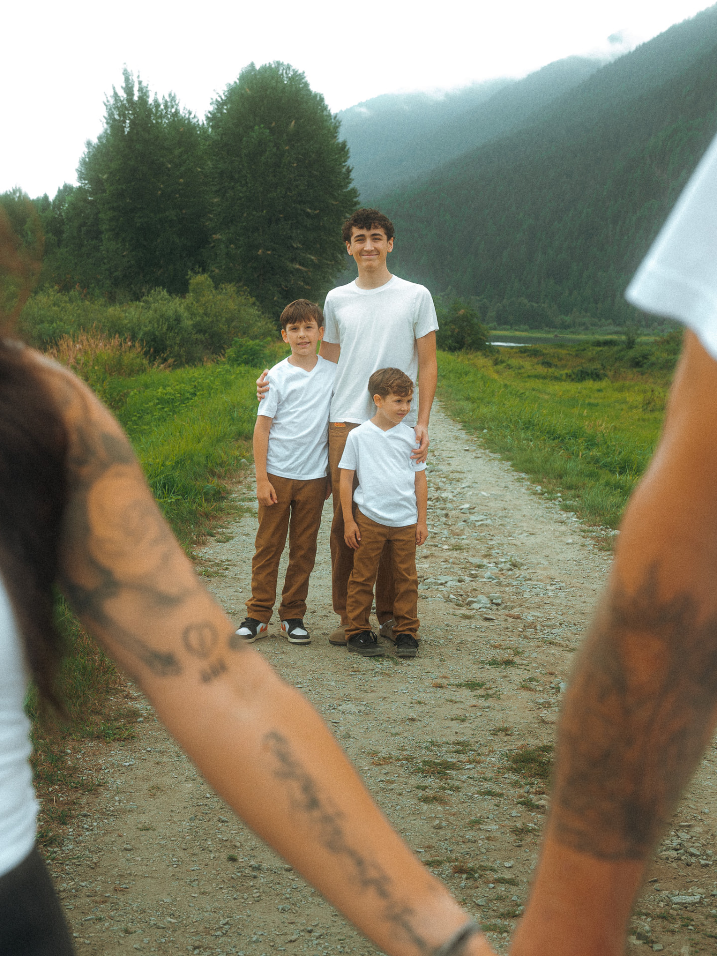 Three brothers framed by their parents' arms on a misty path near Metro Vancouver