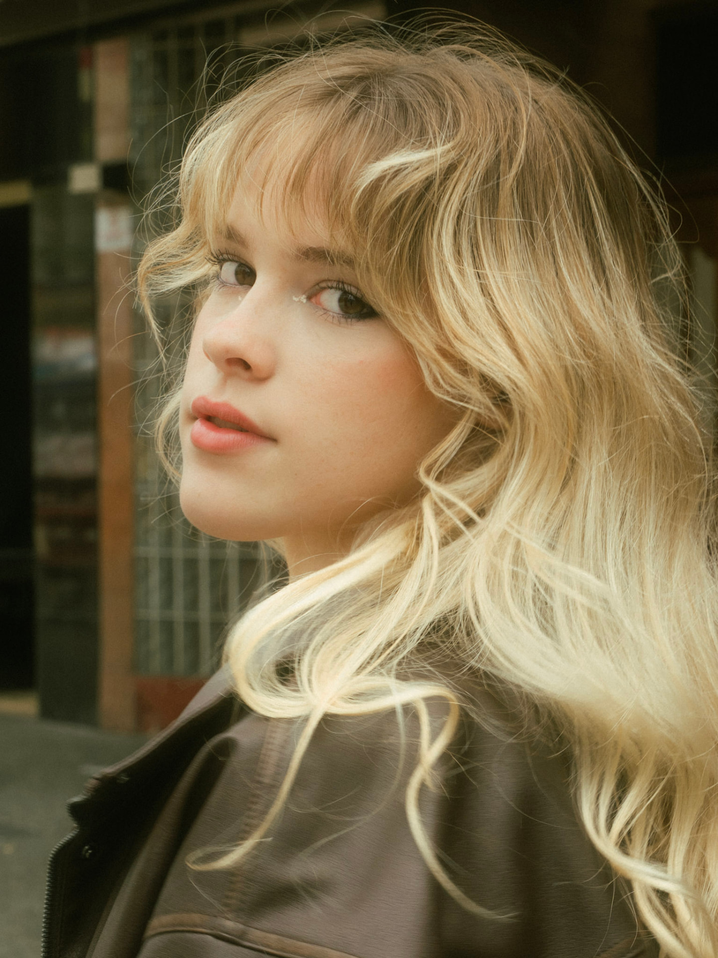 Individual portrait of a young woman looking over her shoulder in a dark brown leather jacket in Vancouver
