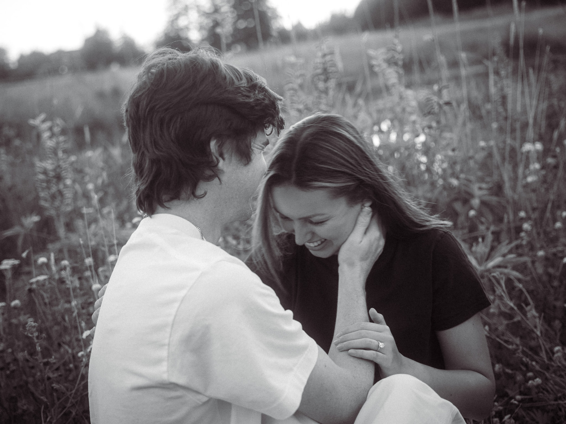 Black and white candid of a couple laughing together in tall grass, Metro Vancouver