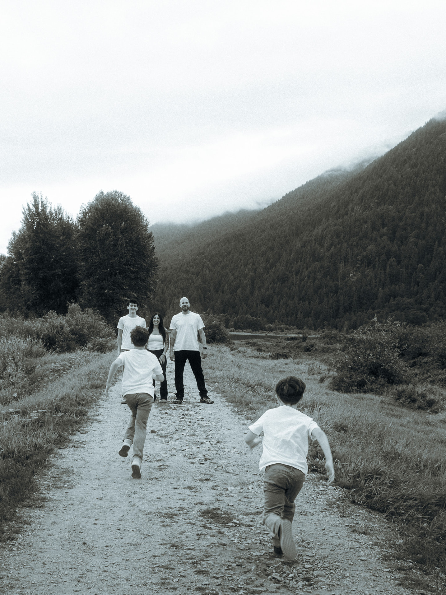 Black and white photo of two young boys running along a mountain path toward their family near Metro Vancouver