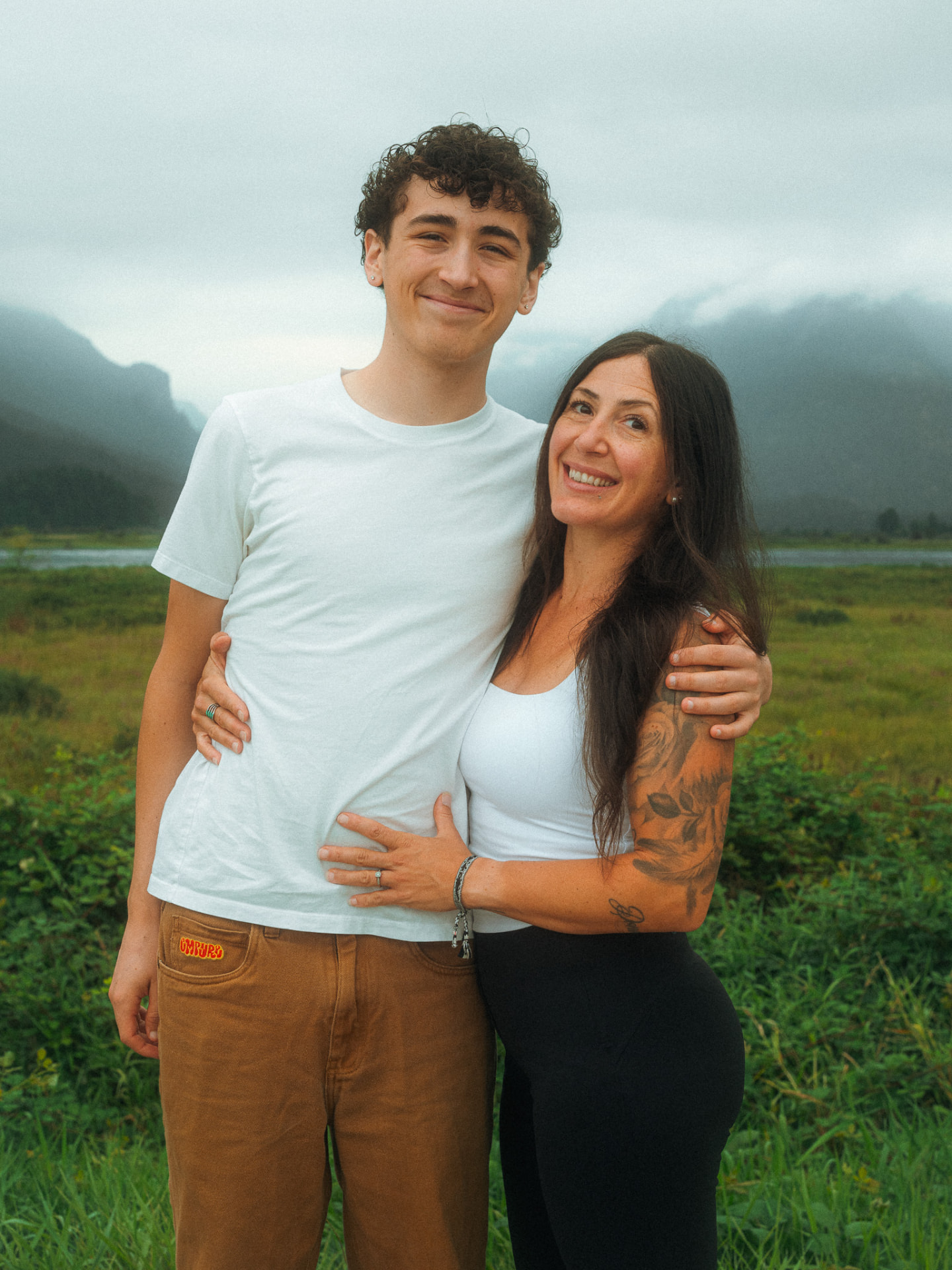 Mother embracing her teenage son against a backdrop of misty mountains near Metro Vancouver