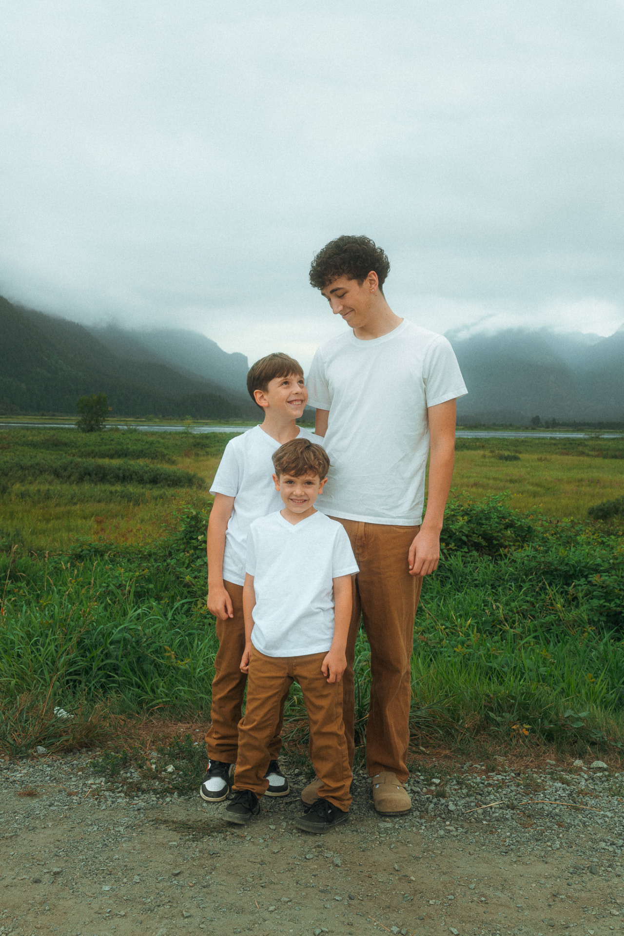 Three brothers sharing a warm moment standing in a misty mountain valley near Metro Vancouver