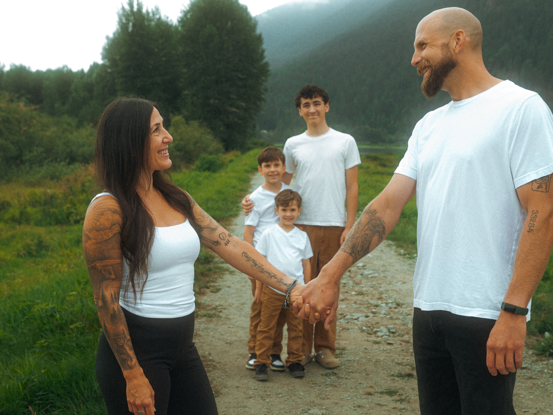 Parents holding hands and smiling while their three sons look on in a scenic mountain valley near Metro Vancouver