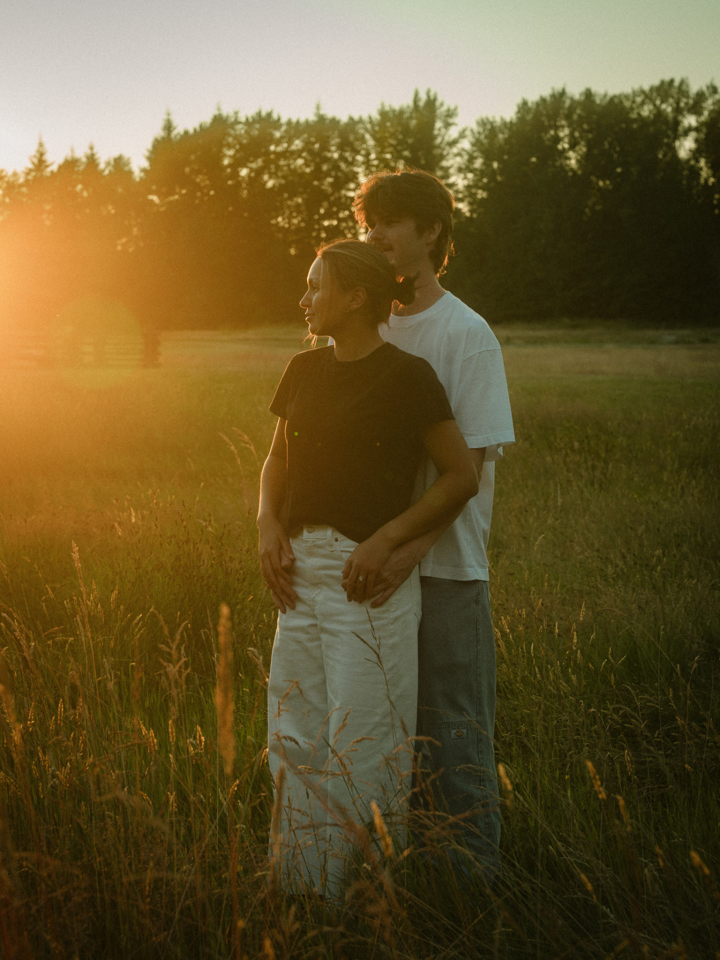 Couple embracing in a sunlit field at golden hour in Metro Vancouver