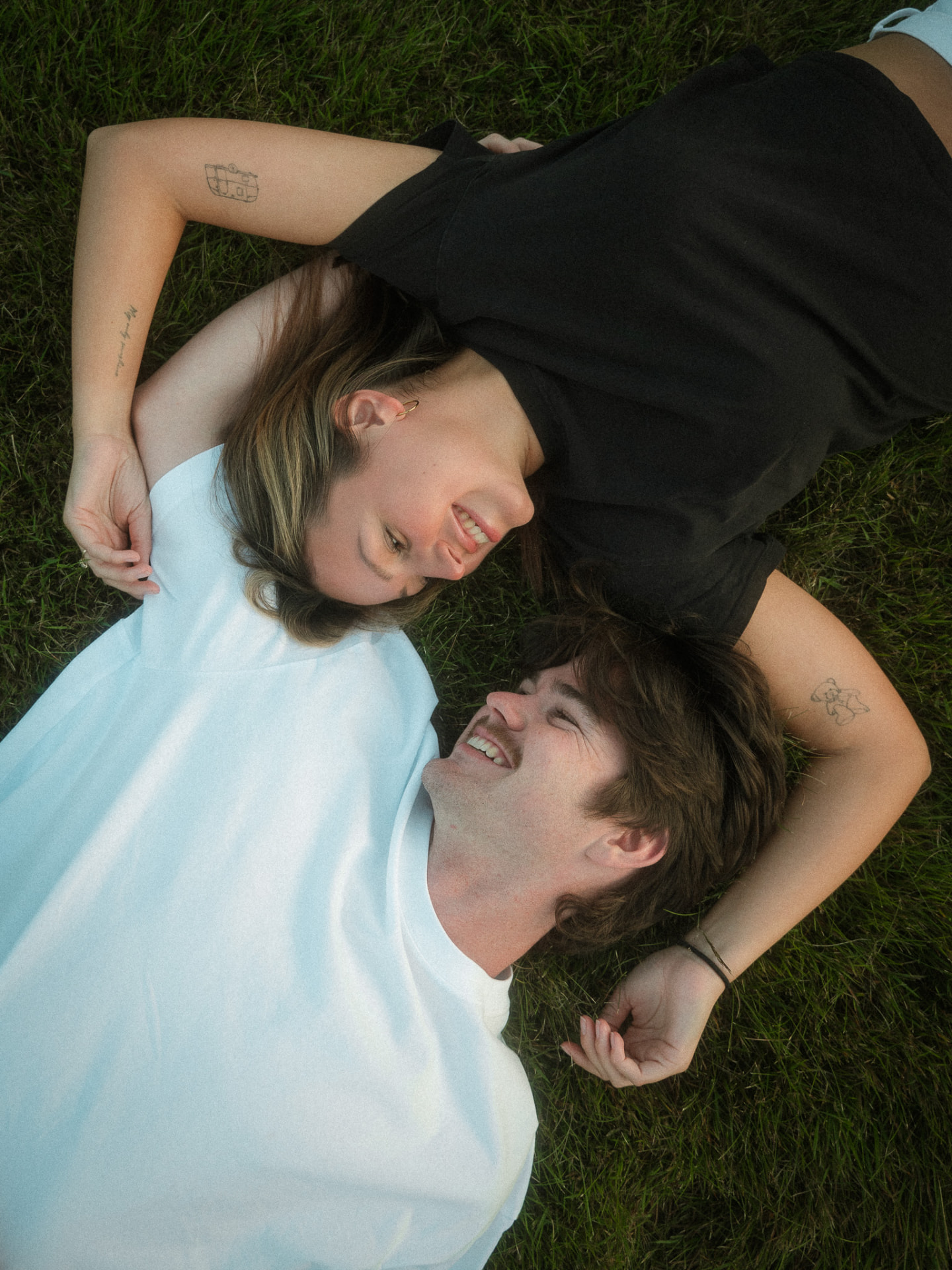 Couple lying head to head on the grass laughing during a Metro Vancouver photo session