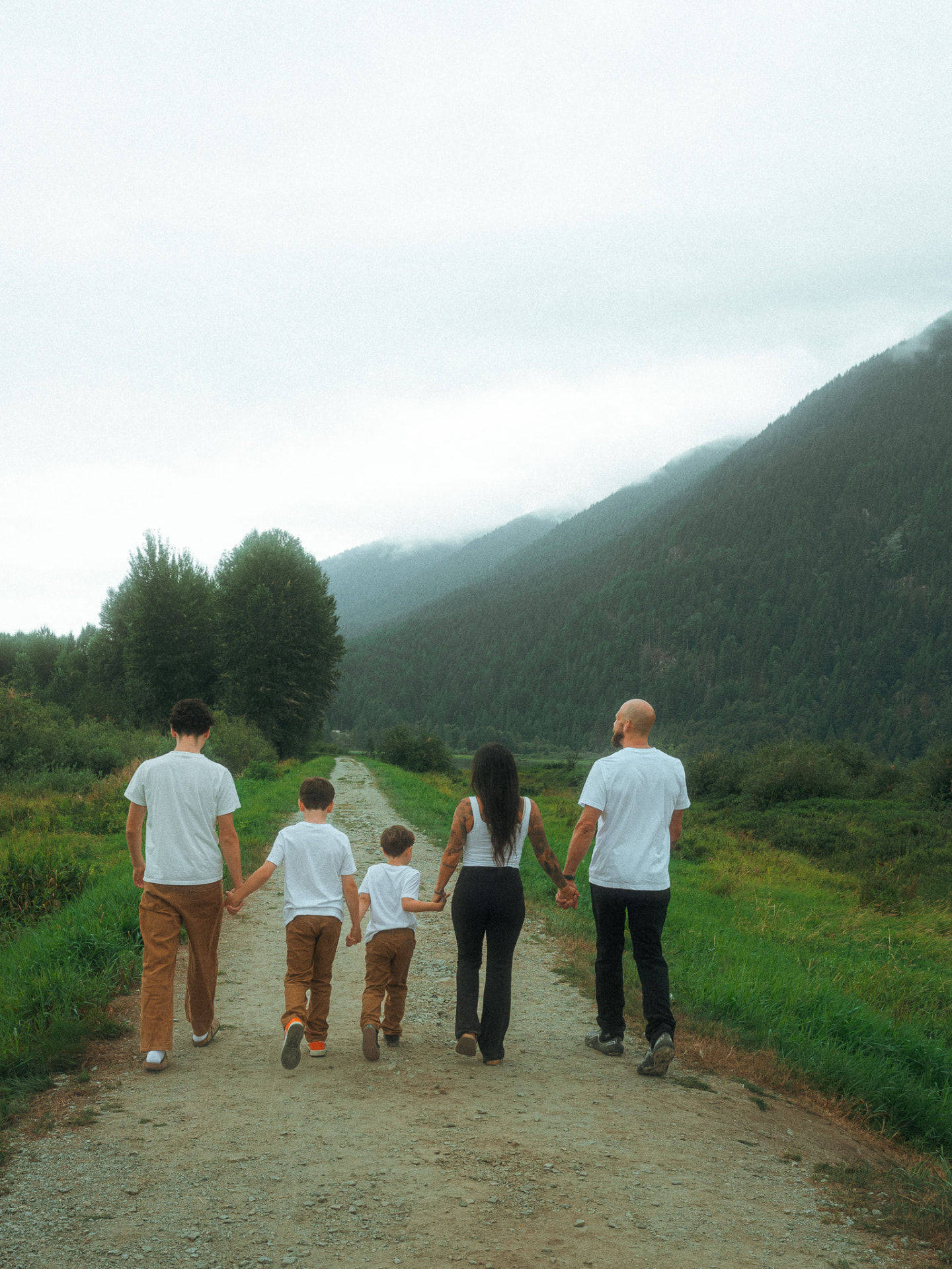 Family of five walking away down a gravel path through a vast green field near Metro Vancouver
