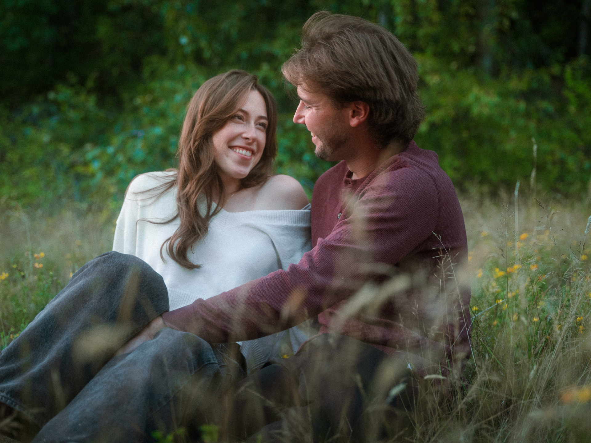 Couple sharing a tender moment sitting together in a grassy meadow near Metro Vancouver